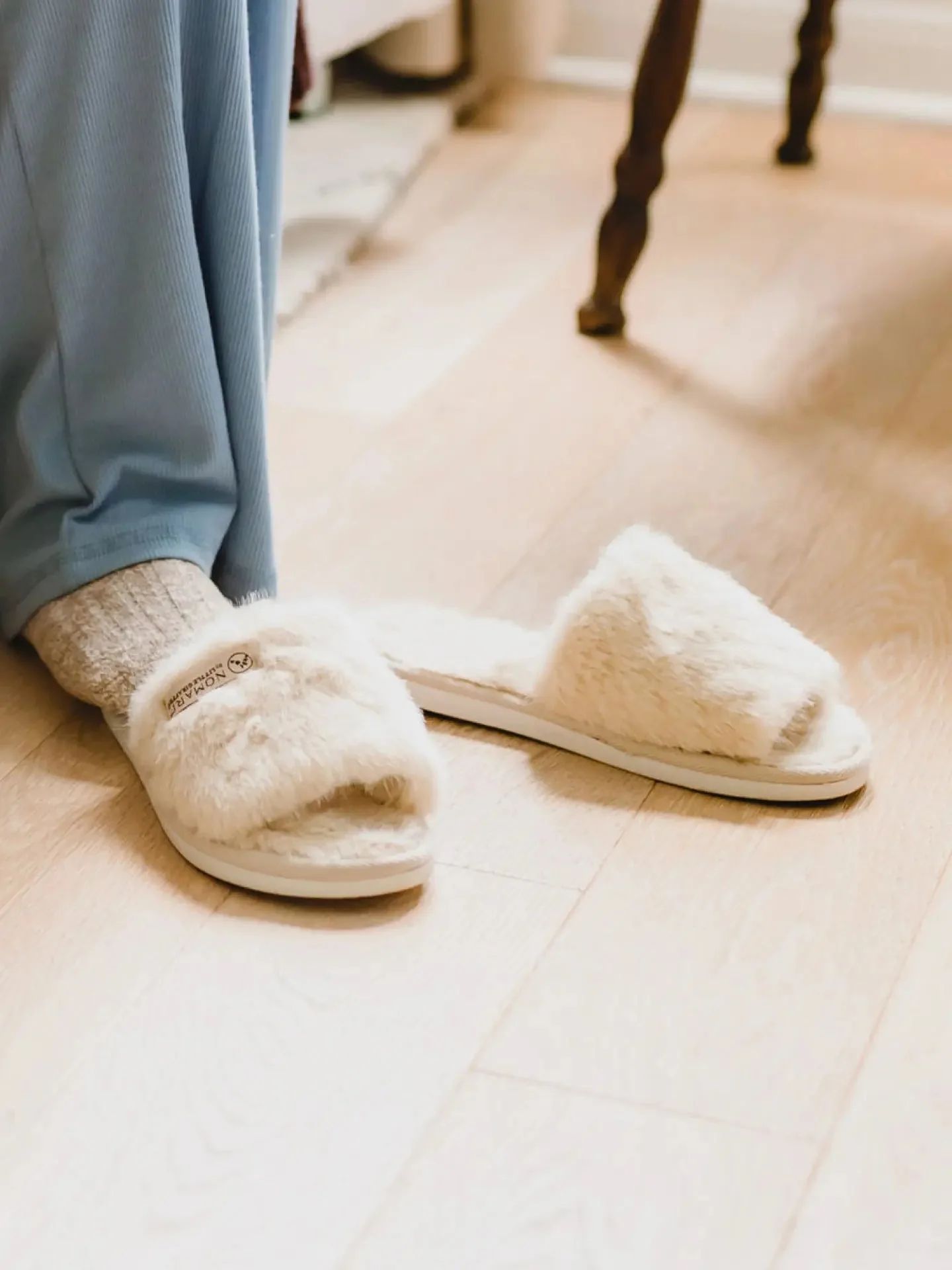 Cream Little Giraffe slippers worn on a light indoor floor