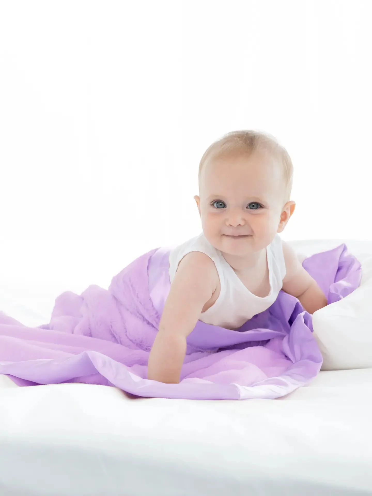Awake baby on a lilac Little Giraffe blanket in a bright room