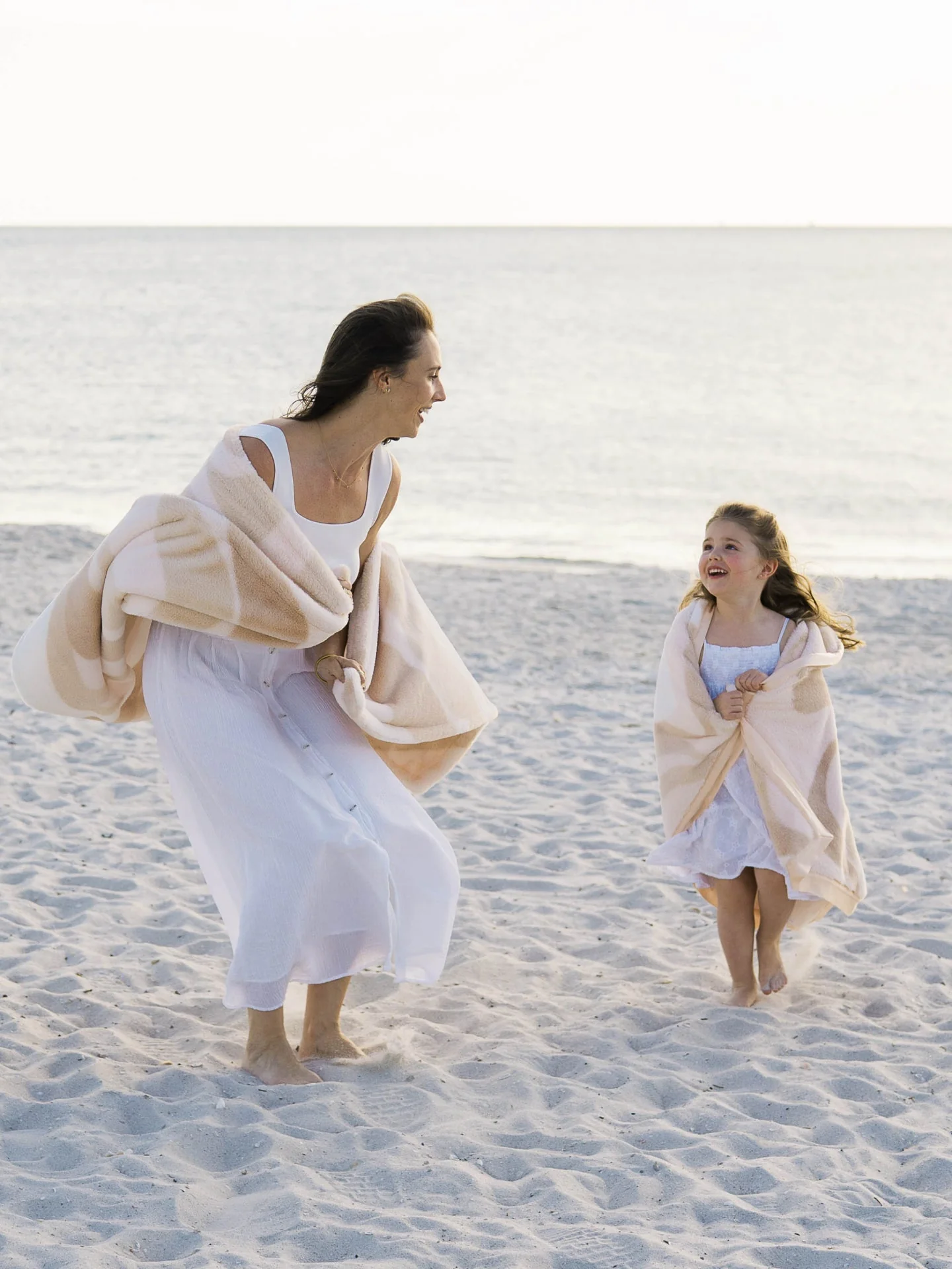 Adult and child playing together on a beach with coordinated Little Giraffe blankets